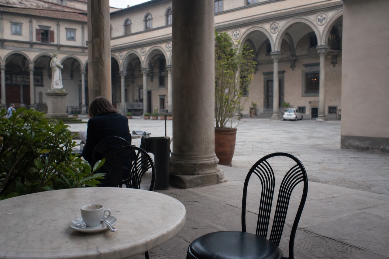 A quiet Florence piazza in spring with cafe tables and stone buildings in soft light