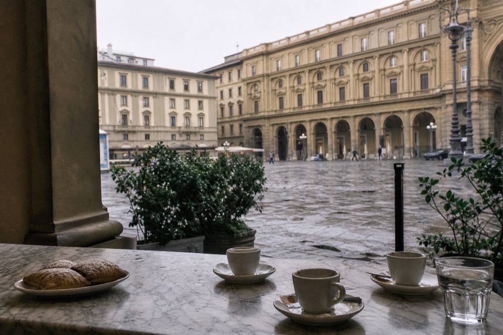 A Florentine street corner with a marble bar counter, espresso cups and a tray of pastries
