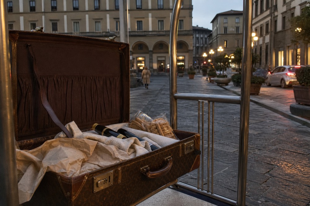 Bottles of olive oil and packets of dry biscuits packed together in an open suitcase