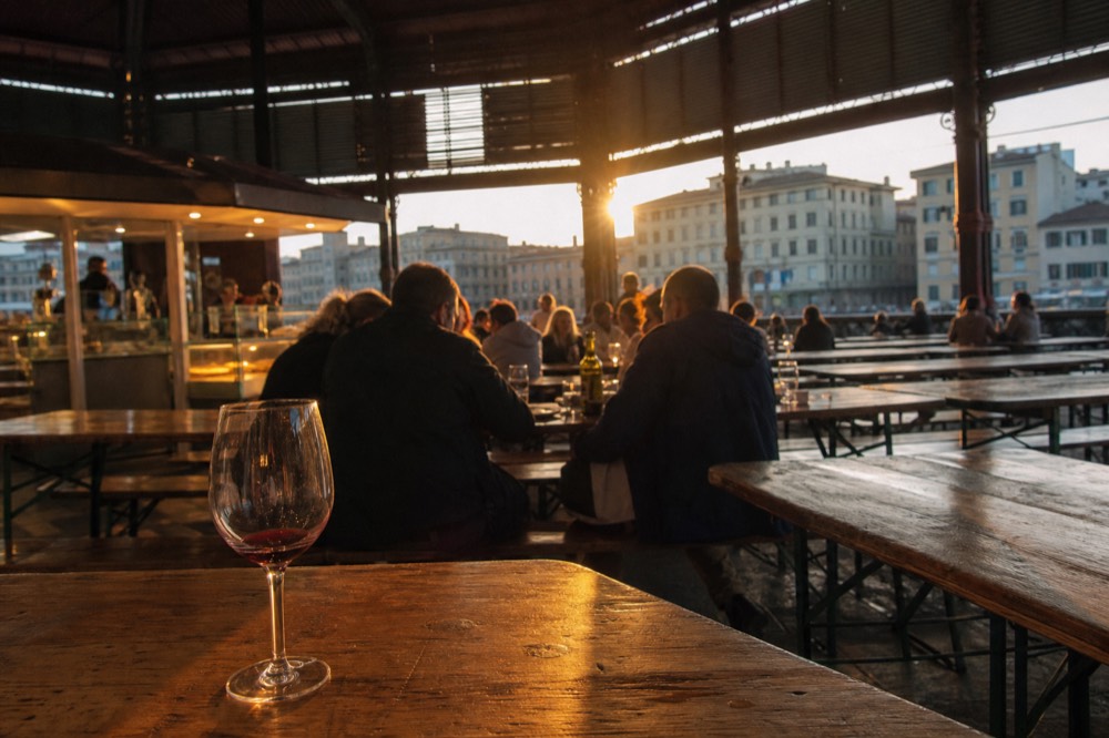 Evening light over food hall counters and communal tables inside a Florence market building