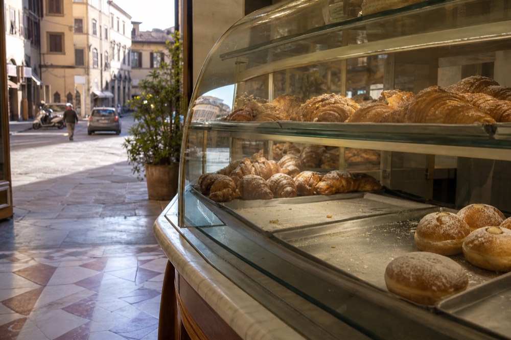 Glass pastry case with cornetti and bomboloni in a Florence pastry shop