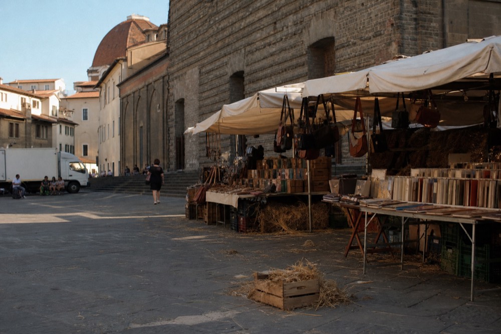 Sunlit piazza in Florence with market stalls and historic facades