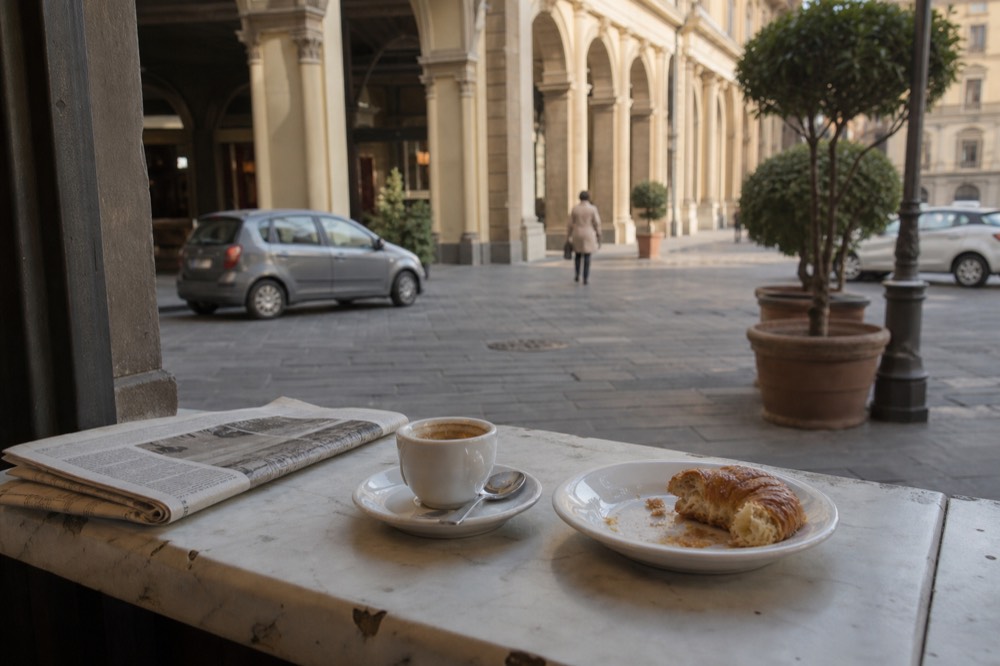 Espresso cup and pastry on a marble bar counter in an Italian cafe