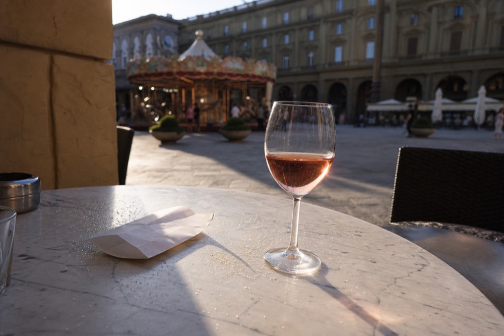 A receipt and wine glass on a marble café table in Florence