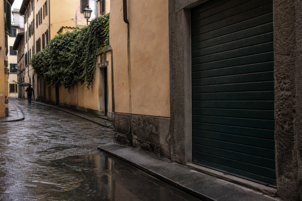 A quiet Florence street corner with a closed shopfront and shuttered windows