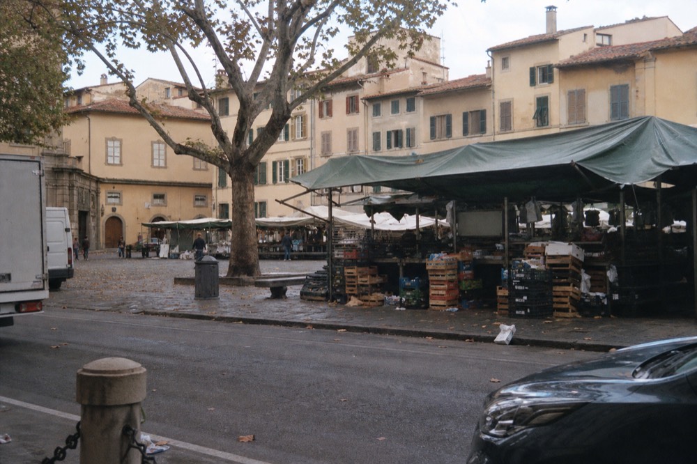 A market street with stalls and awnings in a Florentine neighbourhood