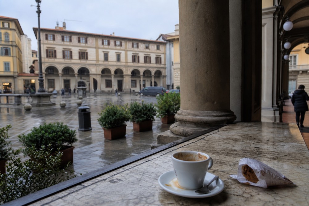 A bar counter with a cup of coffee and a pastry on a marble top