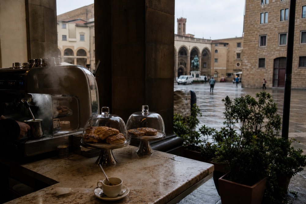 A Florence bar counter with a coffee machine and pastries under glass