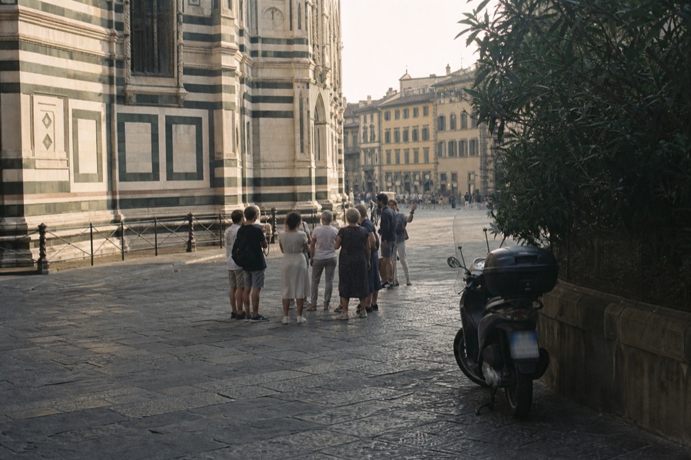 A small group of walkers with a guide pausing at a Florence street corner