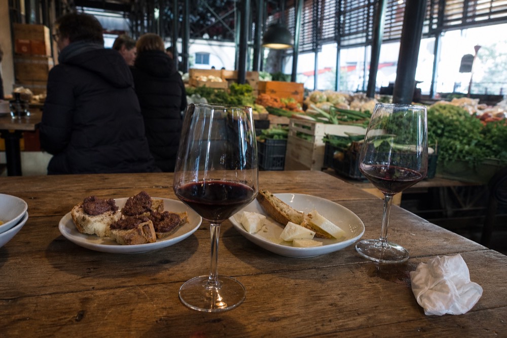 Glasses of red wine on a wooden table beside plates of Tuscan food
