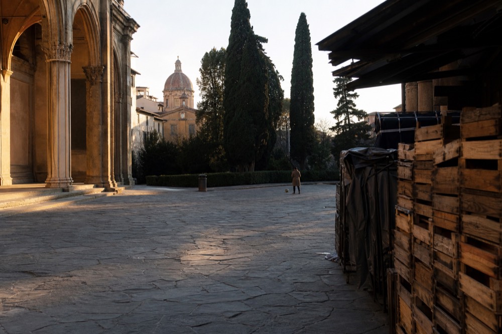 Long evening light across a piazza with market stalls packed away