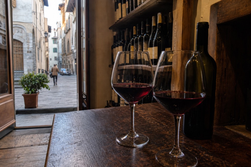 Glasses of red wine on a wooden counter in a small Florentine wine shop