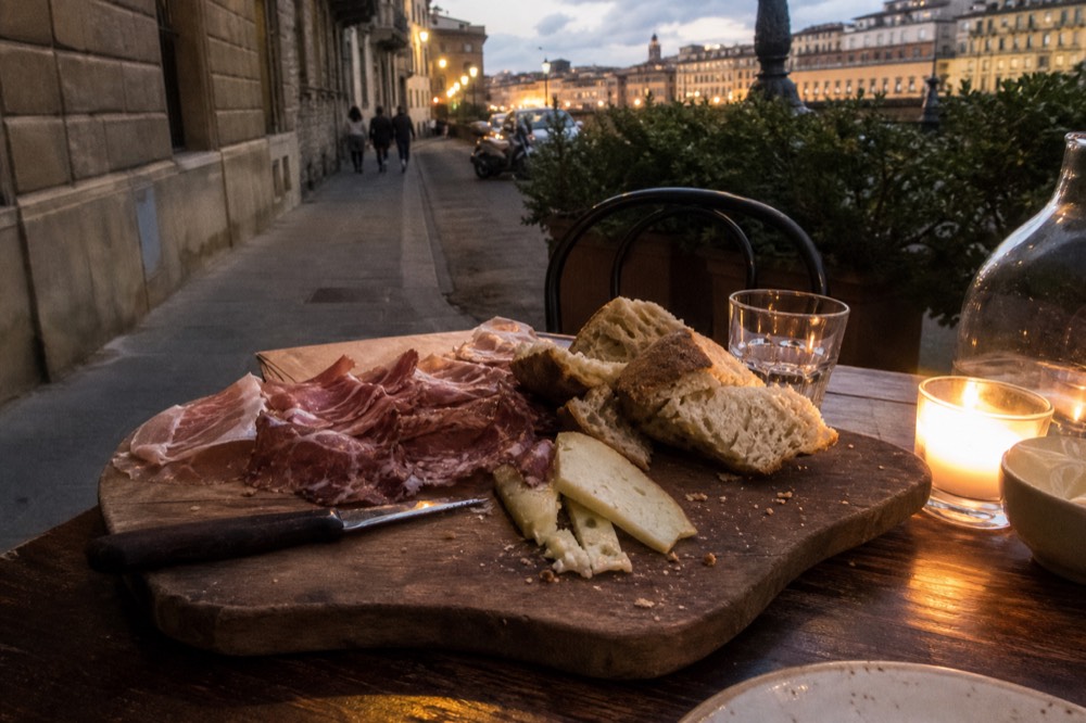 Rustic bread, cured meat and cheese arranged on a wooden board