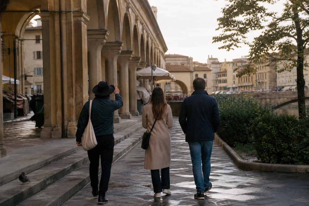 Couple walking with a guide along an arcade of stone arches near a Florence market
