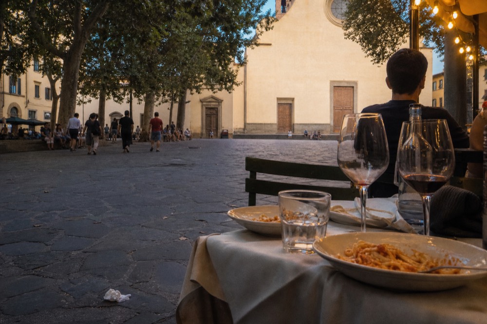 An evening table set with wine glasses and pasta dishes in a Florentine restaurant