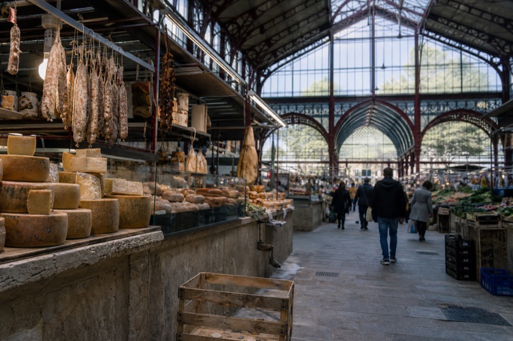 A covered Italian market hall with stalls of cheese, bread and cured meats